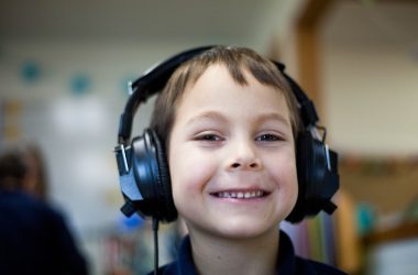 selective focus photography of boy wearing corded headphones