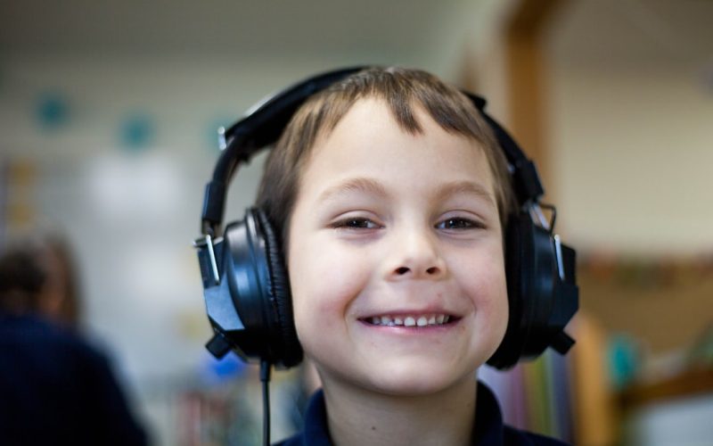 selective focus photography of boy wearing corded headphones