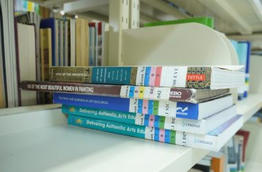 A stack of books sitting on top of a white shelf
