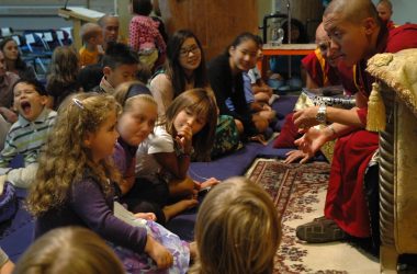 group of children sitting on floor in front of monk