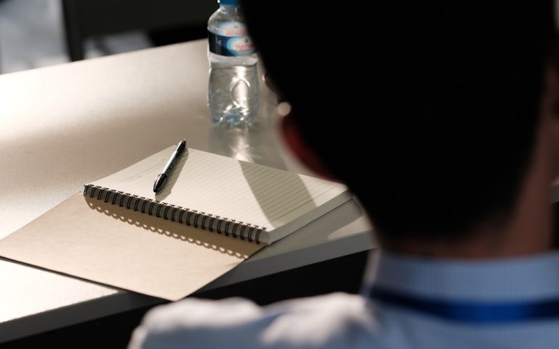 A man sitting at a desk with a notebook and pen