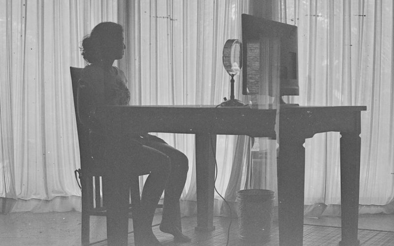 a black and white photo of a woman sitting at a desk
