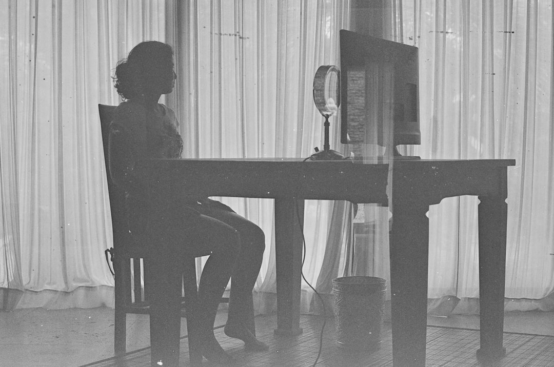 a black and white photo of a woman sitting at a desk
