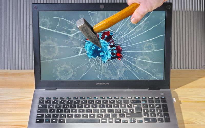 a person holding a pencil and a broken laptop