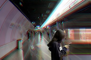 woman in gray hoodie standing in front of train