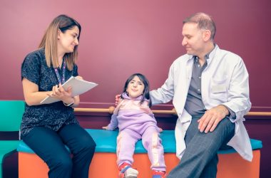 a woman and a man sitting on a bench with a little girl