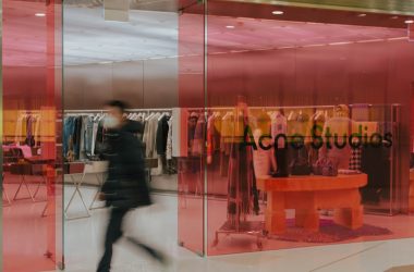 A blurry image of a person walking in front of a clothing store
