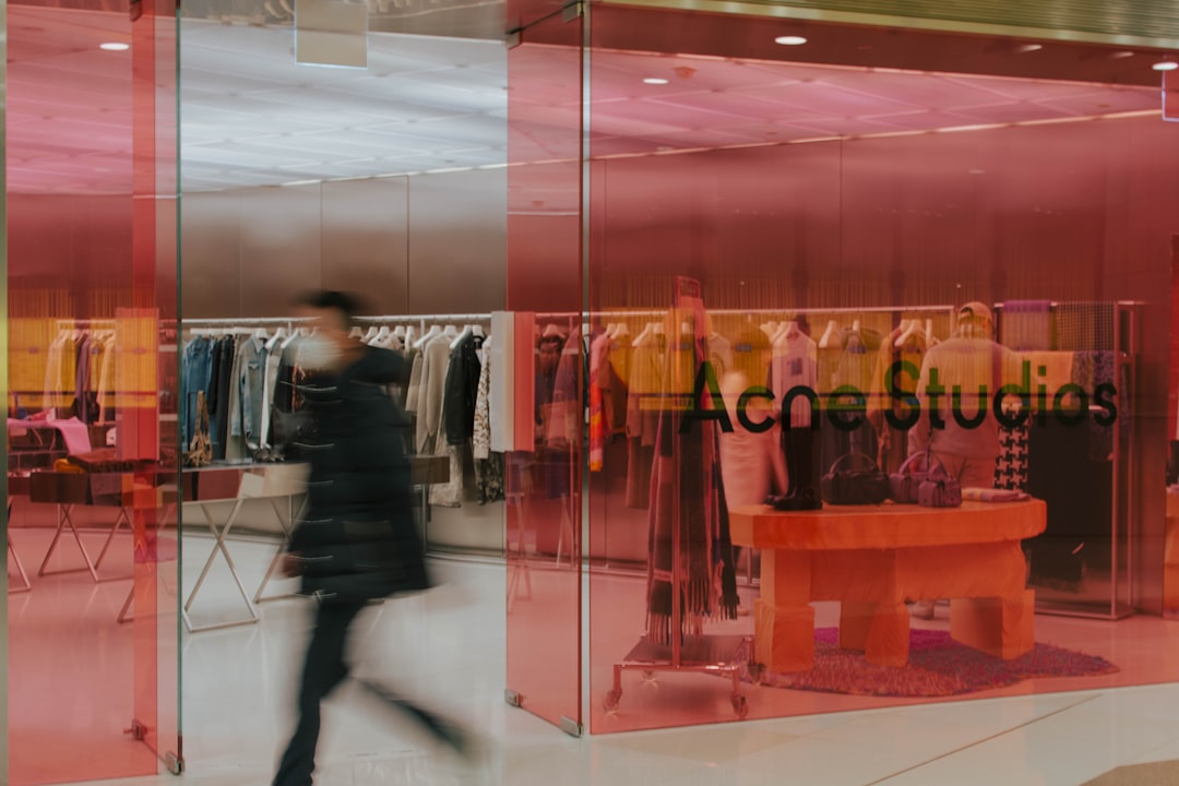 A blurry image of a person walking in front of a clothing store
