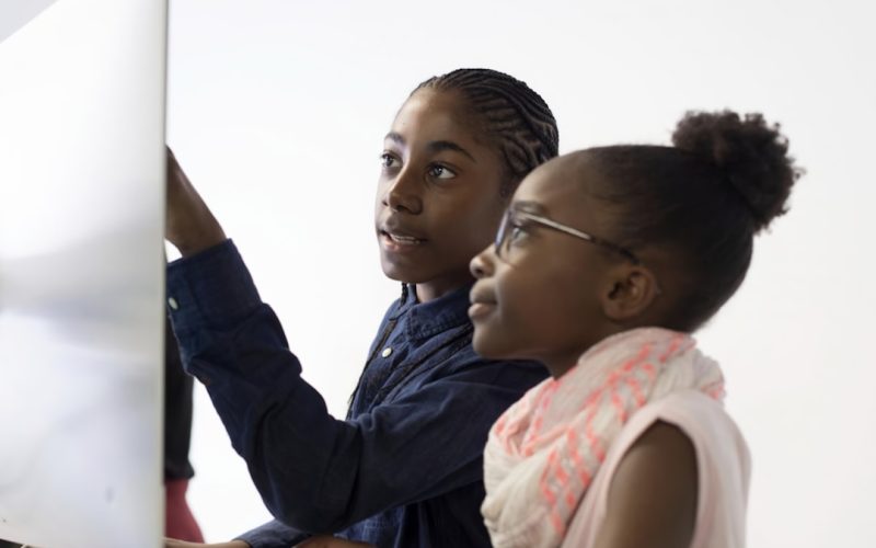 a couple of kids that are looking at a computer screen