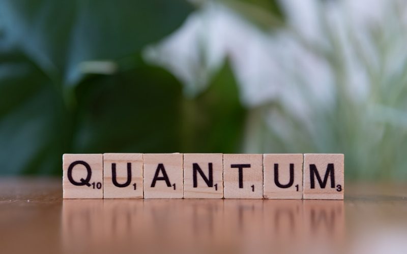 A wooden block spelling the word quanntum on a table