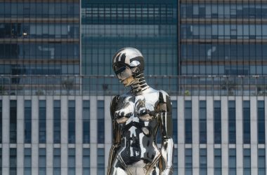 A metallic sculpture stands before a building.