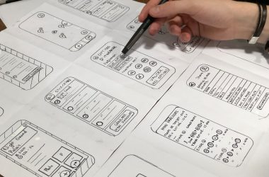 person holding pen near paper