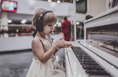 girl wearing headphones sitting in front of white piano