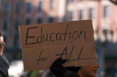 a person holding a sign that says education for all