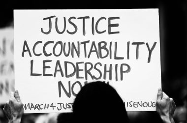 a person holding a sign that says justice acconttability leads to no