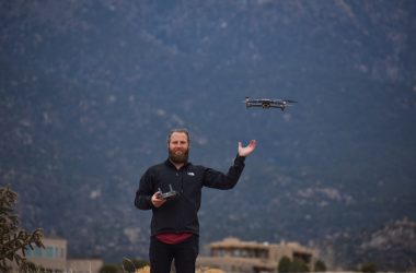 man in black jacket holding black and gray drone