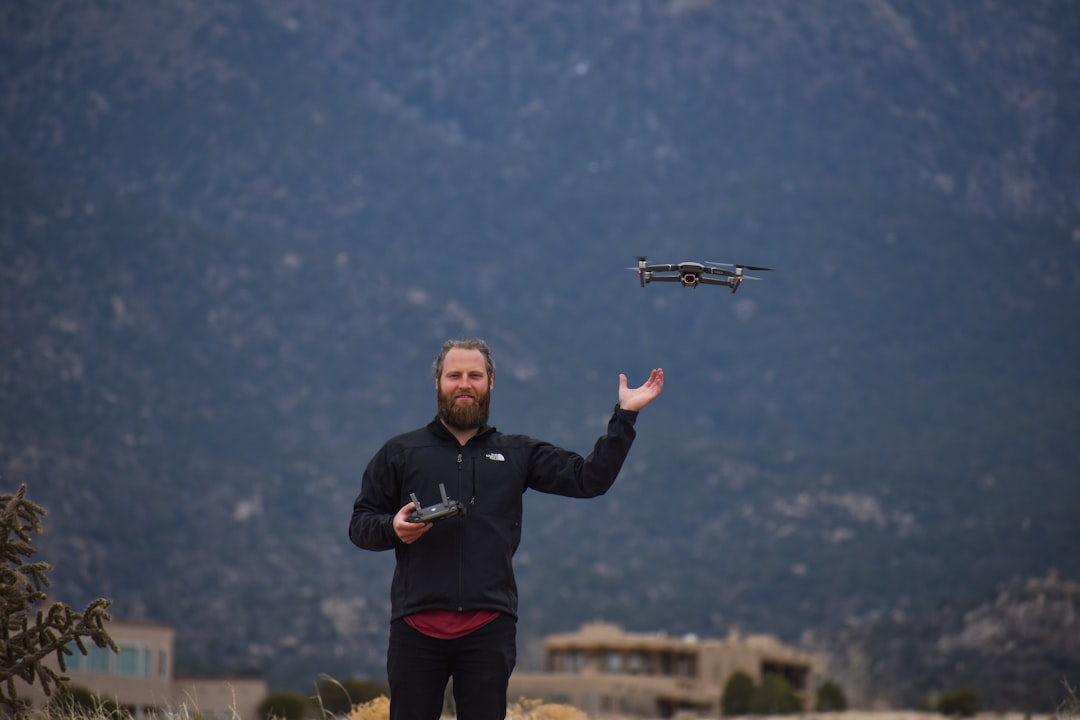 man in black jacket holding black and gray drone