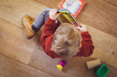 selective focus photography of sitting toddler in red sweater holding book