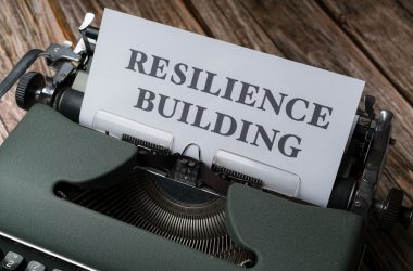 a close up of a typewriter with a paper that reads resilince building