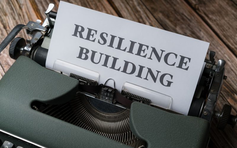 a close up of a typewriter with a paper that reads resilince building