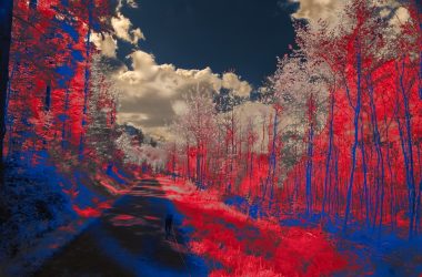a red and blue photo of a person walking down a road