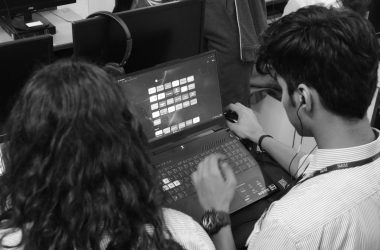 a man and a woman sitting in front of a laptop computer