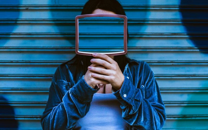 man covering face with mirror