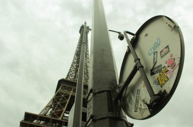 a street sign with stickers on it in front of the eiffel tower