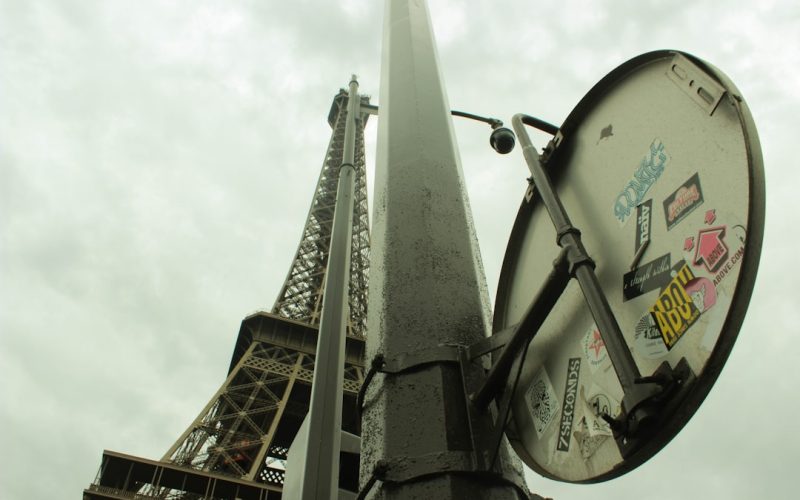 a street sign with stickers on it in front of the eiffel tower