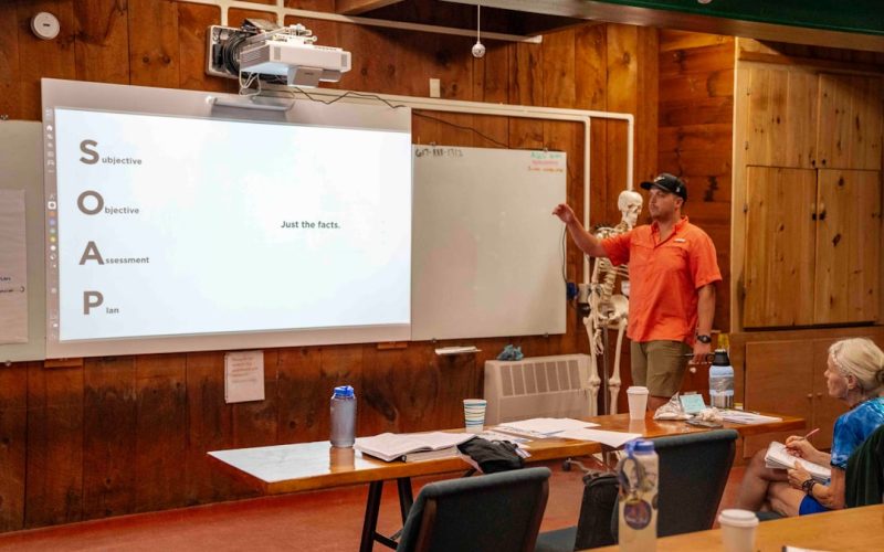 Man presents information on a whiteboard to an audience.