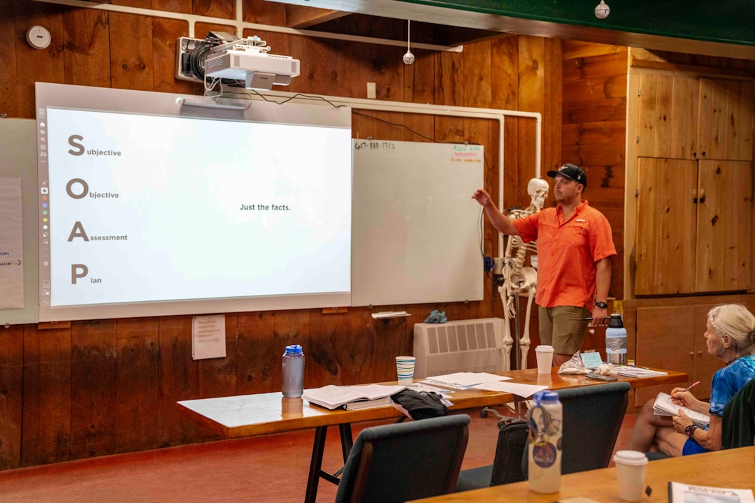 Man presents information on a whiteboard to an audience.
