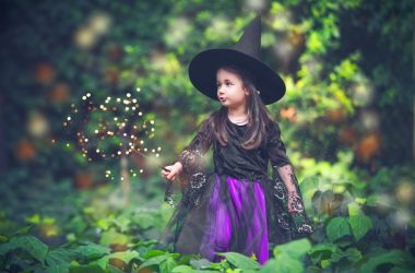 a little girl dressed in a witches costume