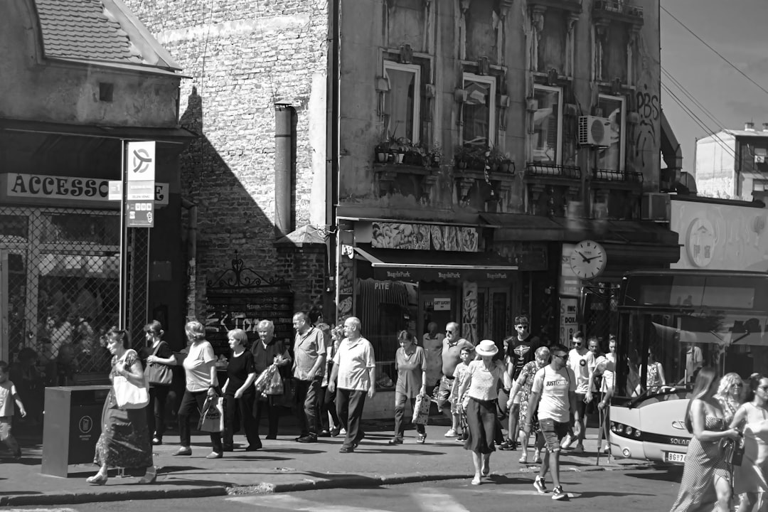 a group of people walking down a street next to tall buildings