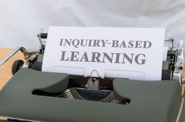 a close up of a typewriter with an inquiry - based learning sign