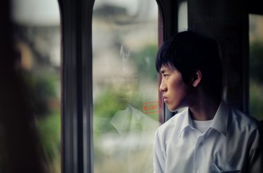 man in dress shirt standing in front of glass door