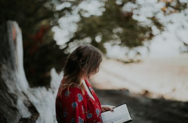 woman holding book on beach