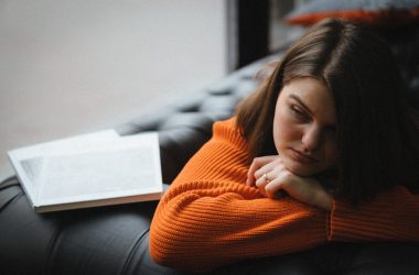 a woman laying on a couch with a book