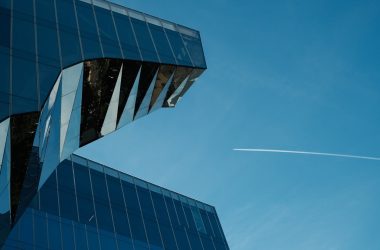a plane flying in the sky over a building
