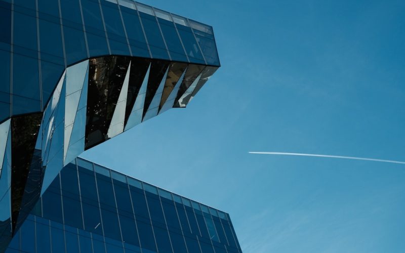 a plane flying in the sky over a building