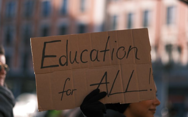 a person holding a sign that says education for all