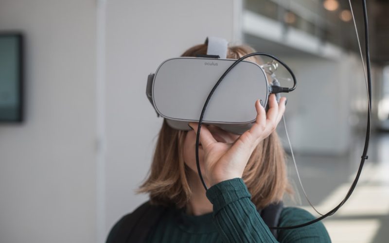 woman in black sweater holding white and black vr goggles