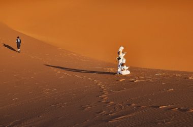 A group of people standing on top of a sandy dune
