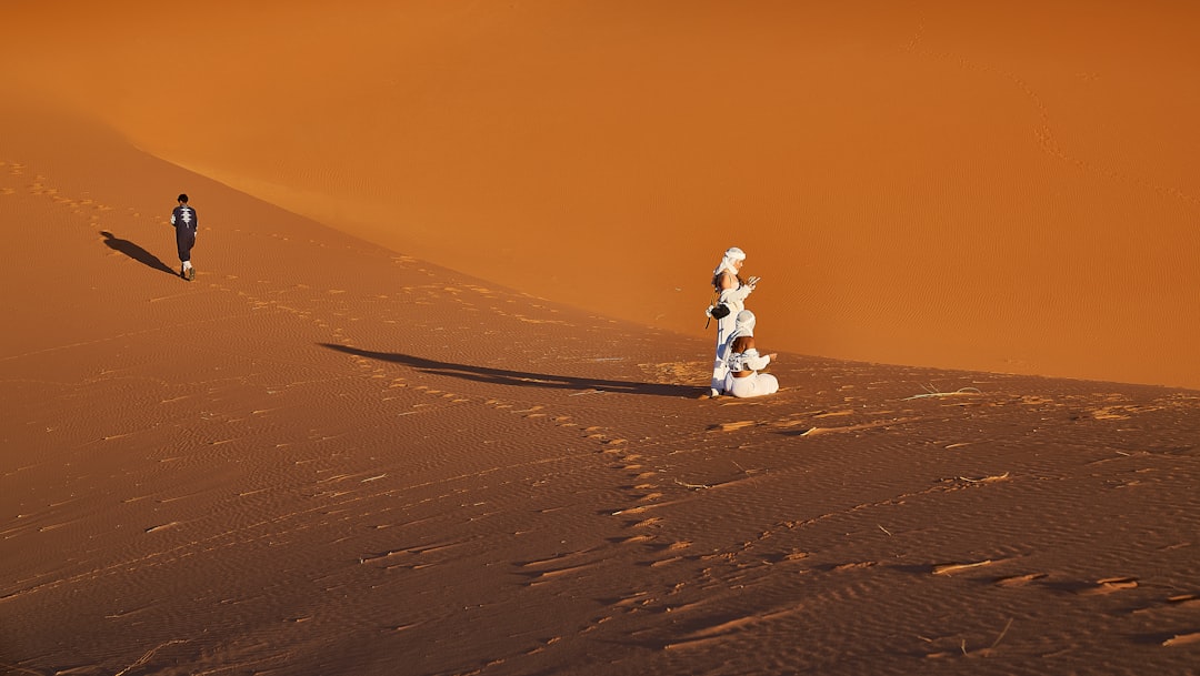 A group of people standing on top of a sandy dune