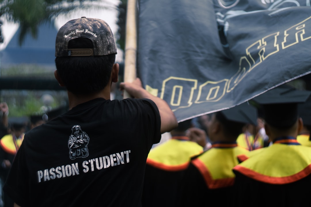 Man in black shirt with "passion student" text holds flag.