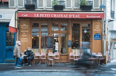 a couple of people sitting at a table outside of a restaurant