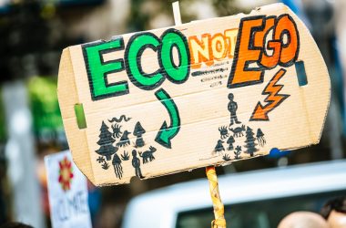 person holding Eco Not Ego signage